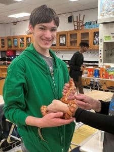 Youth in a green hoodie holding a snake.
