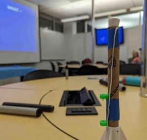 Model rocket sitting on a conference table with computer screens in the background. 