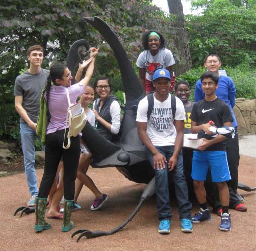 Group of intersectional youth hanging out on a outdoor sculpture.