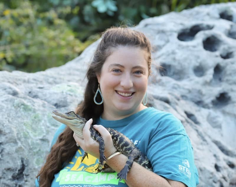 Woman with brown hair holding a small reptile.
